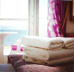 una pila de toallas sentadas encima de una cama en Sea Breeze Hotel en Mastichari