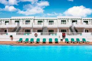 a hotel with chairs and a pool in front of it at Apartamentos Tisalaya in Puerto del Carmen