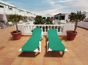 a balcony with green chairs on a roof at Apartamentos Tisalaya in Puerto del Carmen +38 photos