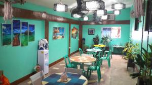 Un comedor con mesas y sillas y paredes azules. en Apo Pension House, en Corón