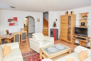 a living room with white furniture and a tv at Ferienhaus Angermeier in Oberstdorf
