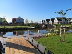 een houten tafel en stoelen naast een rivier met huizen bij Luxurious Water Villa in Uitdam