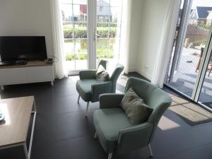 een woonkamer met 3 stoelen en een televisie bij Luxurious Water Villa in Uitdam