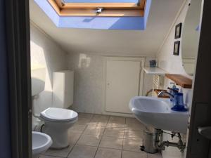 ein Badezimmer mit einem Waschbecken, einem WC und einem Dachfenster in der Unterkunft CAFFELETTI friendly B&B in Torre del Lago Puccini