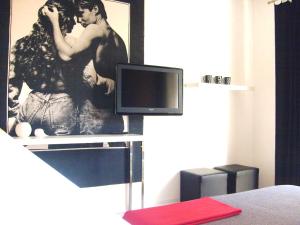 1 dormitorio con TV y una foto de una pareja en I Cugi Metropolis, en Bronte