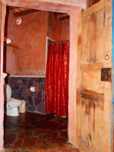 a bathroom with a toilet and a red shower curtain at Hotel Torres Del Fuerte in El Fuerte