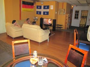 a group of people sitting in a living room watching tv at Oasis Guest House in Kuala Lumpur