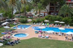 a group of people sitting around a swimming pool at Hotel Luxor in Playa de Palma