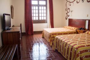 a hotel room with two beds and a television at Hotel Colonial in Manzanillo