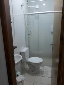 a white bathroom with a toilet and a shower at Flats Di Cavalcanti in Uberlândia