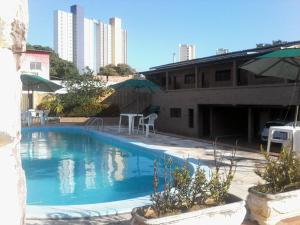 una piscina con mesas y sombrillas junto a un edificio en Pousada Toca do Tato, en Natal