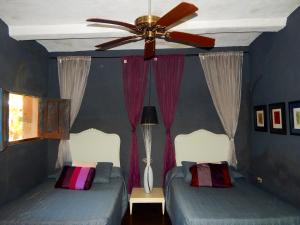 two beds in a blue bedroom with a ceiling fan at Hotel Torres Del Fuerte in El Fuerte