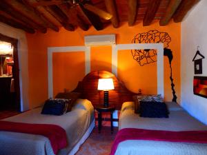 two beds in a room with an orange wall at Hotel Torres Del Fuerte in El Fuerte