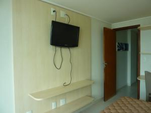 Habitación con TV en una pared con estanterías en Manaira Palace Residence, en João Pessoa