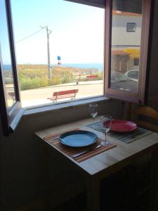 a table with a plate and wine glasses in a window at Casa de Mar @ Porto Côvo in Porto Covo
