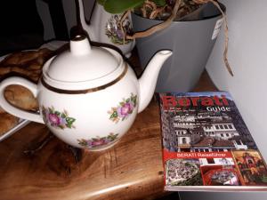 a tea pot sitting on a table next to a magazine at Hotel Omer in Berat