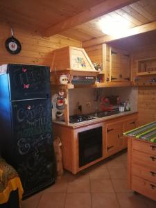 cocina con nevera negra y armarios de madera en Casetta Matilda, en Ardea
