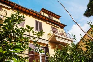 un edificio giallo con balcone e alberi di Hotel Villa Il Castagno a Firenze