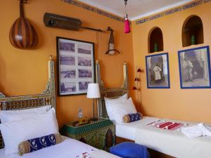um quarto com duas camas e quadros na parede em Dar Sultan em Tânger