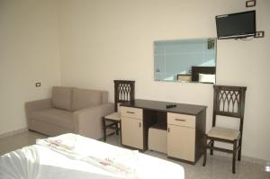 - une chambre avec un lit, un bureau et un canapé dans l'établissement Hotel Aleksandrus Jardin, à Durrës