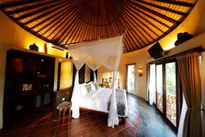 a bedroom with a bed with a mosquito net at Mara River Safari Lodge Bali in Keramas