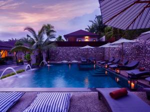 a swimming pool with chairs and umbrellas in front of a house at De Malee Pool Villas - SHA Extra Plus in Ao Nang Beach