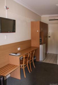 a room with a desk with chairs and a television on the wall at Motel Riverina in Leeton