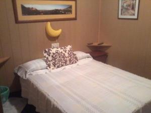 Un dormitorio con una cama blanca con almohadas. en Pensión Moni Albayzin en Granada