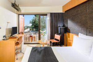 Cette chambre comprend un lit, un bureau et une fenêtre. dans l'établissement Alexander Beach Hotel & Spa, à Alexandroúpolis