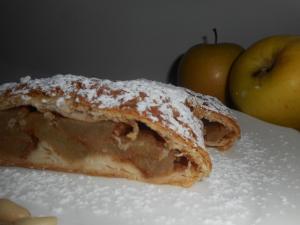 a pastry with powdered sugar on it next to two apples at Garnì Lago Alpino in Molveno