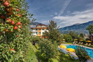 a resort with a pool and some trees and umbrellas at Landhaus Hotel Kristall in Marlengo