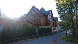 a large brown house with the sun shining on it at Apartament Selaz in Szklarska Poręba