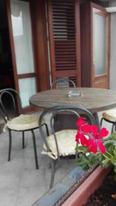 un tavolo con sedie e un fiore rosso su un patio di Il corbezzolo a Linguaglossa