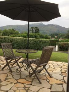 亞斯凱恩的住宿－Maison d'hôtes Urbegia，庭院里设有两把椅子和一张桌子及一把遮阳伞
