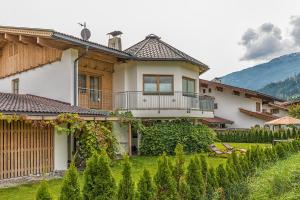 uma casa com uma varanda e um quintal em Sportchalet Zillertal em Uderns