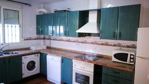 cocina con armarios verdes, lavadora y secadora en Casa La Vega en El Bosque