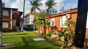 un patio con palmeras y una casa en Pousada das Araras, en Maceió