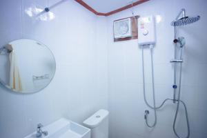 a white bathroom with a mirror and a shower at Romyen House in Ban Nong Nam Khan