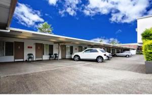 dos autos estacionados en un estacionamiento frente a un edificio en Nambour Lodge Motel en Nambour