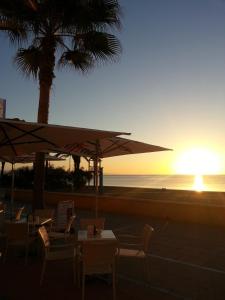 a sunset at the beach with tables and chairs at Hotel Doña Luisa in San Luis de Sabinillas