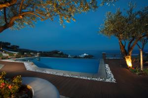 a pool with a view of the ocean at night at Selana Suites in Chrisopigi