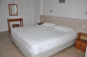 a bedroom with a white bed and a wooden table at Neptune Resort in Kavos