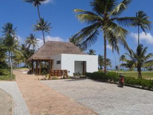 a white building with palm trees in the background at Paribahia in Praia do Forte