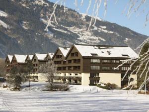ein großes Gebäude im Schnee mit einem Berg in der Unterkunft Sun Valley Apartment in Bad Hofgastein