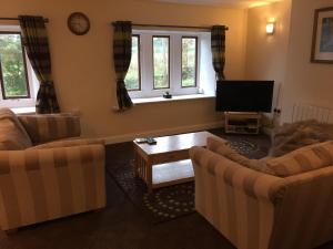 a living room with two couches and a flat screen tv at Winwood Apartment in Holmfirth