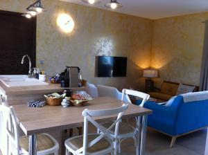 a kitchen with a wooden table and a blue chair at L'Hacienda Piscine chauffée à 28, spa, boulodrome et court de Tennis privés, 2 villas indépendantes in Porto-Vecchio