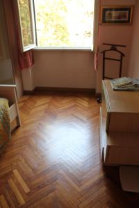 Habitación con suelo de madera y ventana. en Youhome Millelire Apartment, en Milán