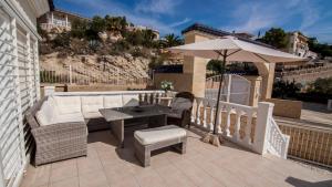 un patio con sofá, mesa y sombrilla en Villa Paradise Campello, en El Campello