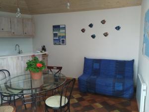 a living room with a glass table and a blue couch at Les Chênes Bleus in Sainte-Marie-de-Ré