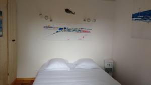 a bedroom with a white bed and a painting on the wall at Les Chênes Bleus in Sainte-Marie-de-Ré